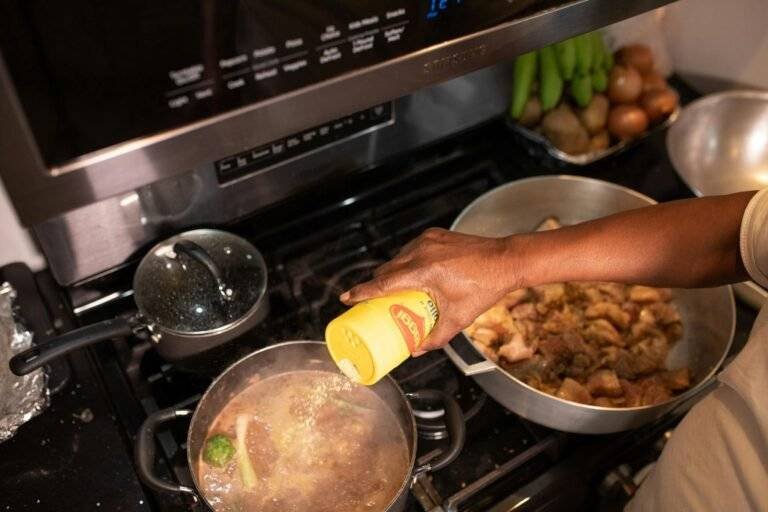 A person seasoning a delicious meat dish on a stove, capturing the essence of home cooking.